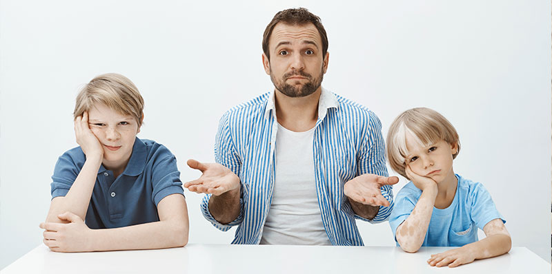 father sitting table with bored upset sons shrugging with raised palms being clueless how raise boys alone