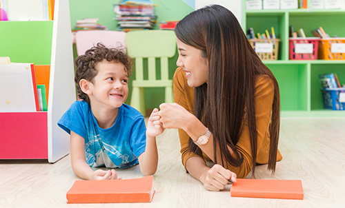Young woman teacher teaching little boy kindergarten classroom with happiness relaxation education elementary school