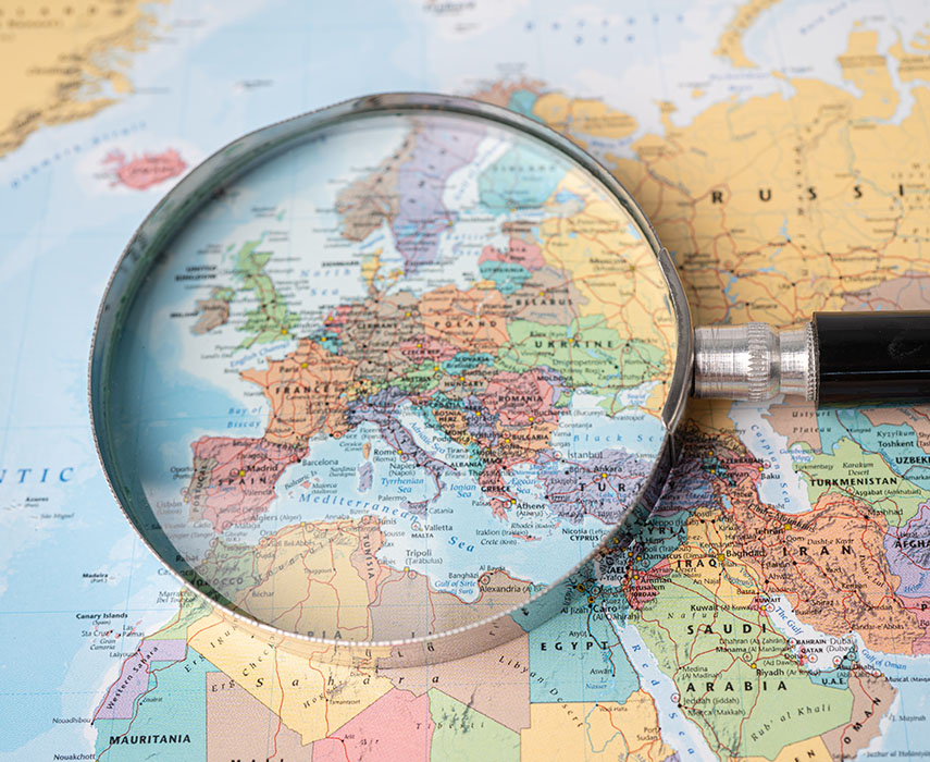 Magnifying glass highlighting Europe on a colorful world map, symbolizing global and European online services.